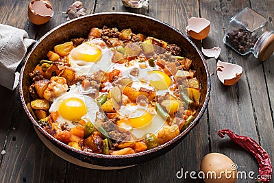 Homemade Hearty Breakfast Skillet with Eggs Potatoes and minced meat on wooden table Stock Photo