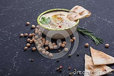 Homemade hummus, chickpea beans, rosemary with pita on black stone table. Middle Eastern traditional and authentic arab cuisine Stock Photo