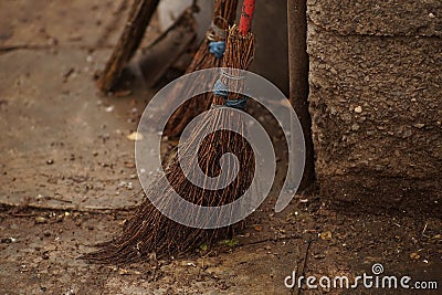 Homemade knitted broom on a wet floor in a rural yard Stock Photo
