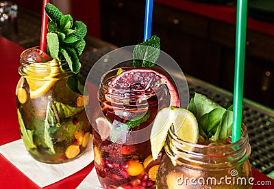 Homemade lemonade ice tea colorful icetea drink with fresh sweet fruits mint leaves in glass on the rocks with straw Stock Photo