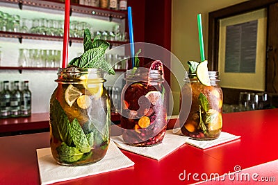 Homemade lemonade ice tea colorful icetea drink with fresh sweet fruits mint leaves in glass on the rocks with straw Stock Photo