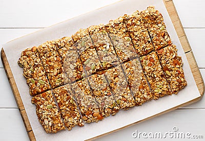 Homemade no bake granola bars with oat flakes, honey, dried apricots and seeds on white baking paper. Stock Photo