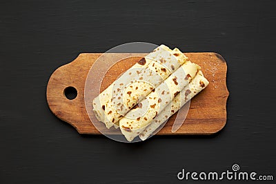 Homemade Norwegian Potato Flatbread Lefse with Butter and Sugar on a rustic wooden board on a black background, top view. Stock Photo