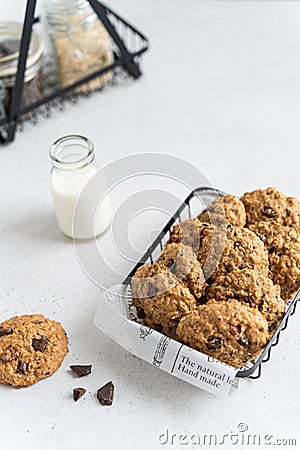 Homemade oatmeal cookies with banana, oats, chocolate drops and nuts on a wooden board and a bottle of milk on a white background Stock Photo