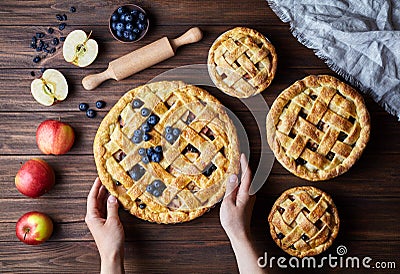 Homemade organic apple pies bakery products hold female hands on dark wooden kitchen table with raising, bluberry Stock Photo