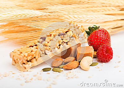 Homemade organic granola cereal bar with nuts and dried fruit on white background with oats and raw wheat. Strawberry and raspberr Stock Photo