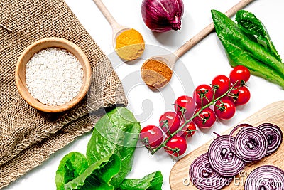 Homemade paella ingredients composition with rice, tomato, onion on white table background top view Stock Photo