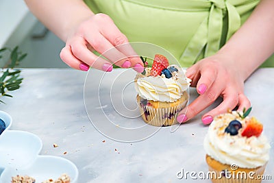 Homemade pastry. Woman cooking cakes. Tasty birthday cupcake on table. Confectioner decorate cupcakes with cream cheese and Stock Photo