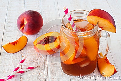 Homemade peach iced tea in a mason jar glass with a white wood background Stock Photo