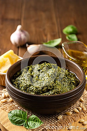 Homemade pesto sauce in ceramic bowl and ingredients on wooden background Stock Photo