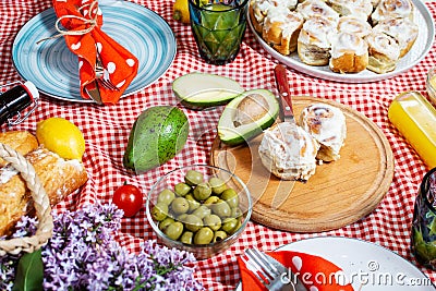 Homemade picnic with fresh fruits, vegetables, salad, orange juice, flowers and baguette on a red plaid Stock Photo