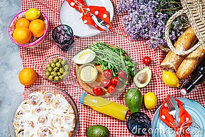 Homemade picnic with fresh fruits, vegetables, salad, orange juice, flowers and baguette on a red plaid. Beautiful still life Stock Photo