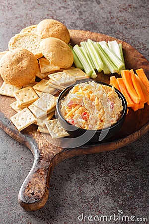Homemade Pimento Cheese Spread with Crackers and Veggies closeup on the wooden board. Vertical Stock Photo