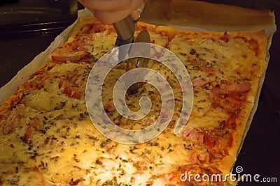 Homemade pizza beeing cut up Stock Photo