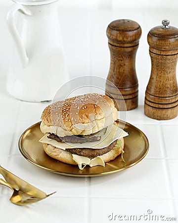 Homemade Premium Cheese Hamburger on Golden Plate, White Table Stock Photo