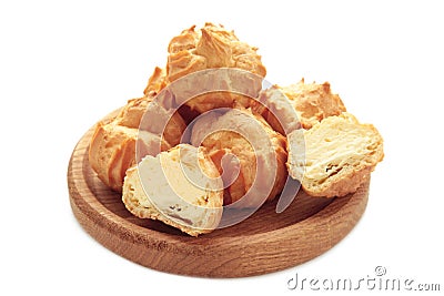 Homemade profiteroles with cream on wooden plate isolated on white background. Fresh baked golden profiterole Stock Photo