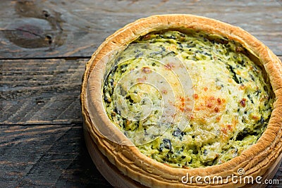 Homemade puff pastry quiche lorraine with leeks swiss gruyere and soft goat cheese with scrumptious golden crust on wood board Stock Photo