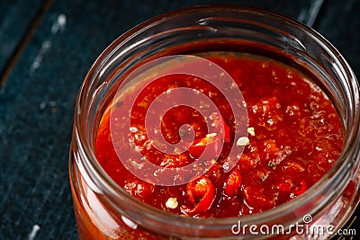 Homemade red hot chili pepper sauce in a glass bowl on a dark wooden background Stock Photo
