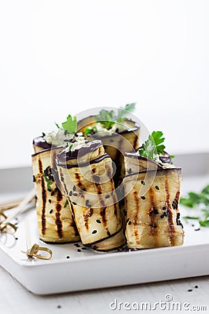 Homemade rolled eggplant (aubergine) grilled appetizers with cottage cheese, nuts, black sesam and parsley Stock Photo