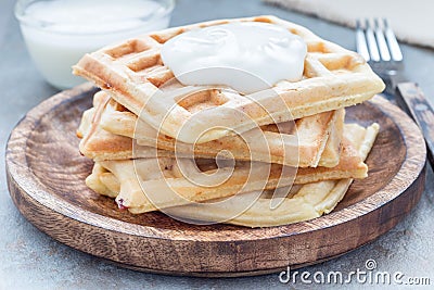 Homemade savory belgian waffles with bacon and shredded cheese, served with plain yogurt, on wooden plate, horizontal Stock Photo
