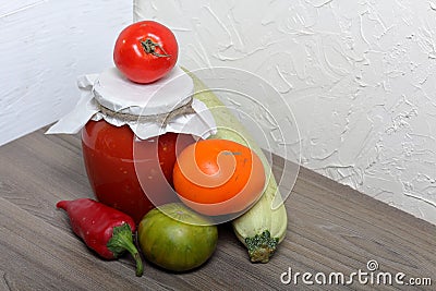 Homemade seasonal preparations. In glass jars, tomato paste. The neck of the cans is wrapped in paper and tied with rope. Nearby Stock Photo