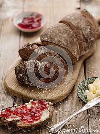 Homemade sliced rye bread on a wooden table and a sandwich with Stock Photo