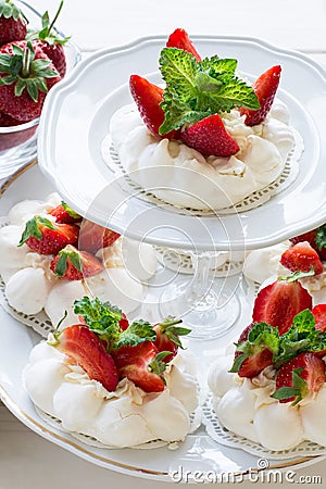 Homemade small strawberry pavlova meringue cakes with mascarpone cream and fresh mint leaves Stock Photo