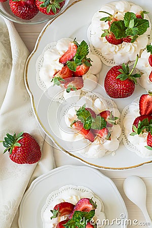 Homemade small strawberry pavlova meringue cakes with mascarpone cream and fresh mint leaves Stock Photo