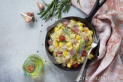 Homemade snacks on a stone or slate background. Warm salad with potatoes sauerkraut and smoked sausages. Flat lay. Stock Photo