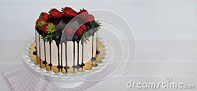 HOMEMADE SUMMER CAKE DECORATED WITH ICING CHOCOLATE, RASPBERRIES, STRAWBERRIES AGAINST WHITE WOODEN BACKGROUND Stock Photo