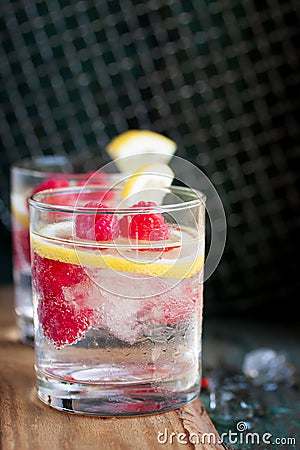 Homemade summer cold raspberry lemon cocktail with sparkling water and crushed iced in glasses on a vintage background Stock Photo