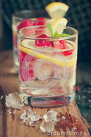 Homemade summer cold raspberry lemon cocktail with sparkling water and crushed iced in glasses on a vintage background Stock Photo