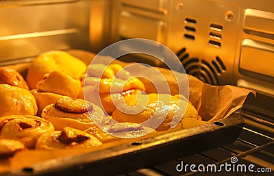 Homemade sweet cinnamon roll baking on a sheet in oven Stock Photo