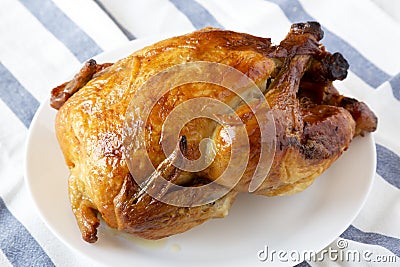 Homemade tasty rotisserie chicken on white plate, side view. Close-up Stock Photo