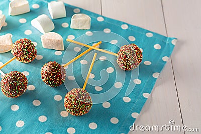 Homemade tiny cakes - cakepops for children`s birthday on a white wooden background. Stock Photo