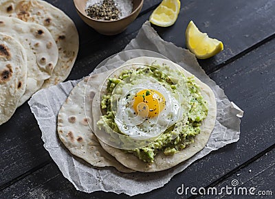 Homemade tortilla with mashed avocado and a fried quail egg. Stock Photo
