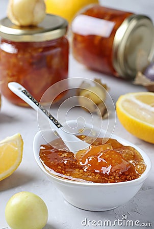 Homemade transparent physalis jam with lemon in bowl and glass jars on light gray background Stock Photo