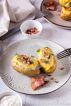 Homemade twice baked potatoes with cheese and bacon on a plate on the table. Vertical view Stock Photo