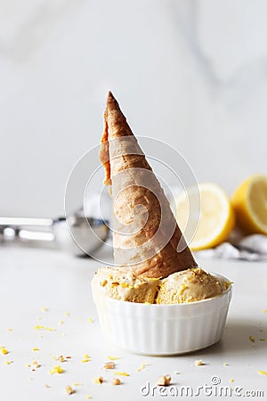 Homemade upside down lemon ice cream. Ice cream cone, sprinkled with zest. On a white table Stock Photo