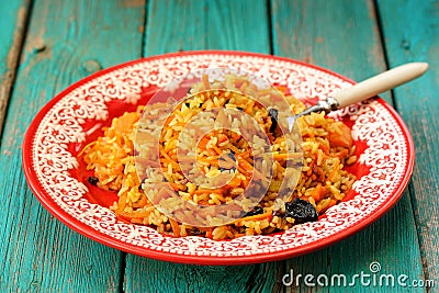 Homemade vegan pumpkin pilaf with prunes in red plate on turquoi Stock Photo