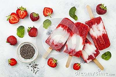 Homemade vegan strawberry coconut milk popsicles with chia seeds on rustic white background. Stock Photo