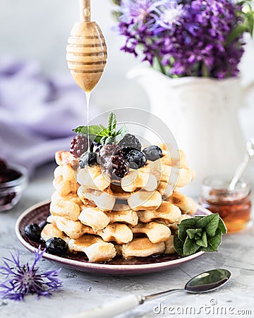 Homemade waffles with berries and honey, a Cup of coffee on the table with a bouquet of lilacs Stock Photo