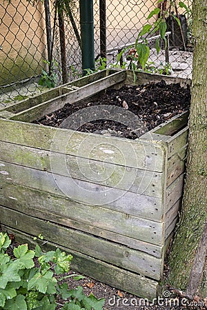 Homemade wooden compost bin in the garden. Recycling organic biodegradable material and household waste in composter. Best organic Stock Photo