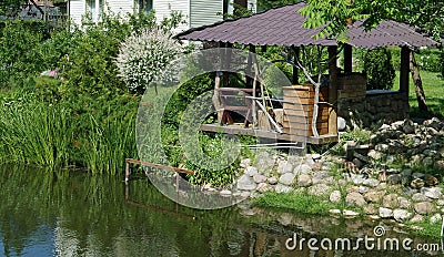 Homemade wooden gazebo on the shore of a village pond Stock Photo