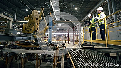 Homens olham uma máquina que trabalha em uma fábrica de tijolos Homens olham uma máquina que trabalha em uma fábrica de tijolos