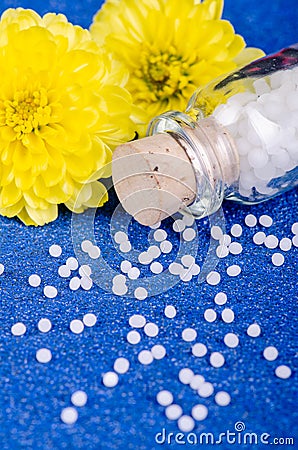 Homeopathic globules on a blue background with yellow flowers Stock Photo
