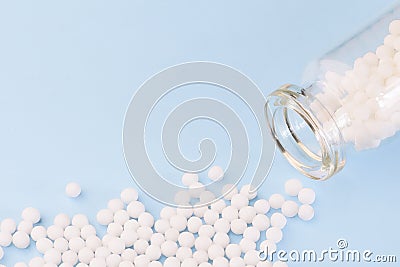 Homeopathic globules and glass bottle on blue background. Alternative Homeopathy medicine. Stock Photo