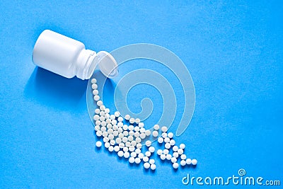 Homeopathic globules and plastic bottle on blue background. Healtcare and pills concept. Vitamins, prebiotics, probiotics. Flat l Stock Photo