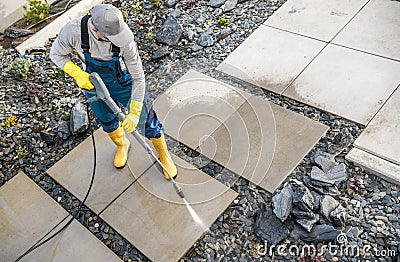 Homeowner Washing Out Dirt From His Garden Concrete Paths Using Pressure Washer Stock Photo