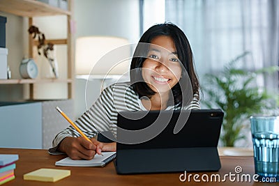 Homeschooling Asian girl doing homework And study online with tablet at the desk night. Portrait of Asia child happiness and Stock Photo